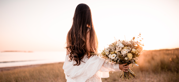 femme de dos portant un bouquet de fleurs
